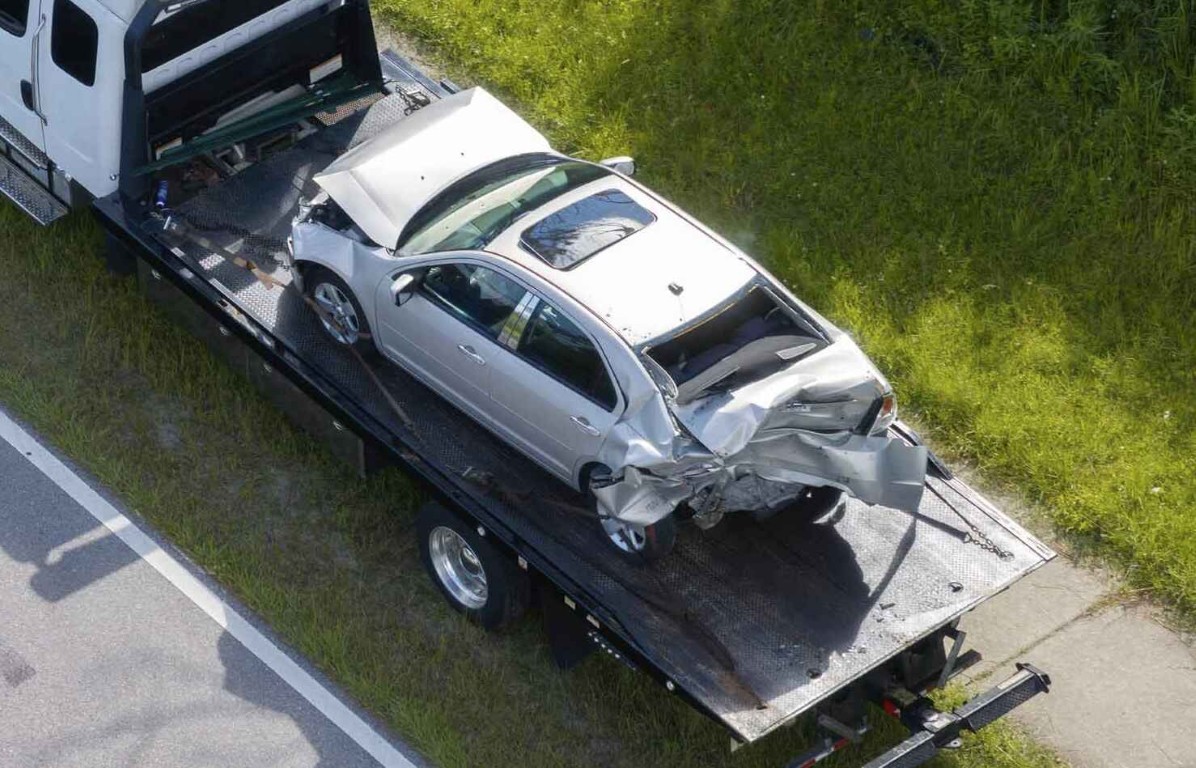 Flatbed tow truck recovering a damaged car after an accident in Deer Park, NY